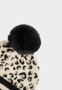 Beanie lavorato a maglia beige con motivo a stampa leopardata nera e marrone, completato da un grande pom-pom nero soffice e un bordo a coste neri.