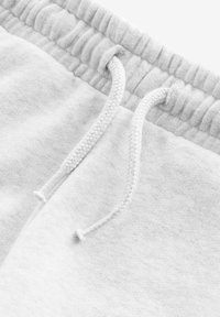 Lysegrå bomulds sweatpants har en elastisk talje med snøre og viser en blød tekstur samt et simpelt, udekoreret design.