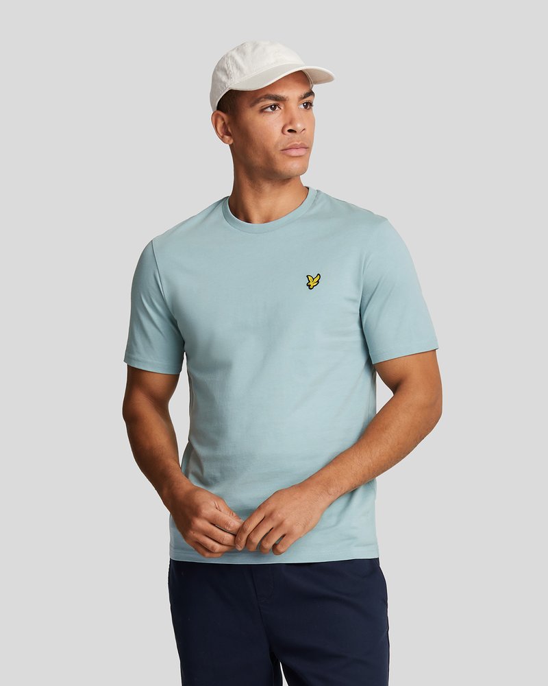 T-shirt en coton bleu clair avec un col rond, des manches courtes et un petit accent logo jaune sur la poitrine gauche.