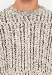 Strickpullover mit strukturiertem Muster in hellbeige und braun. Verfügt über ein vertikales Streifendessin mit einem gerippten Kragen und einer offenen Webart.