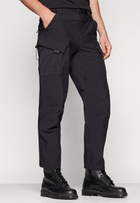 Svarta cargobyxor i lätt material, med flera fickor, en vanlig passform och en avsmalnande bendesign.