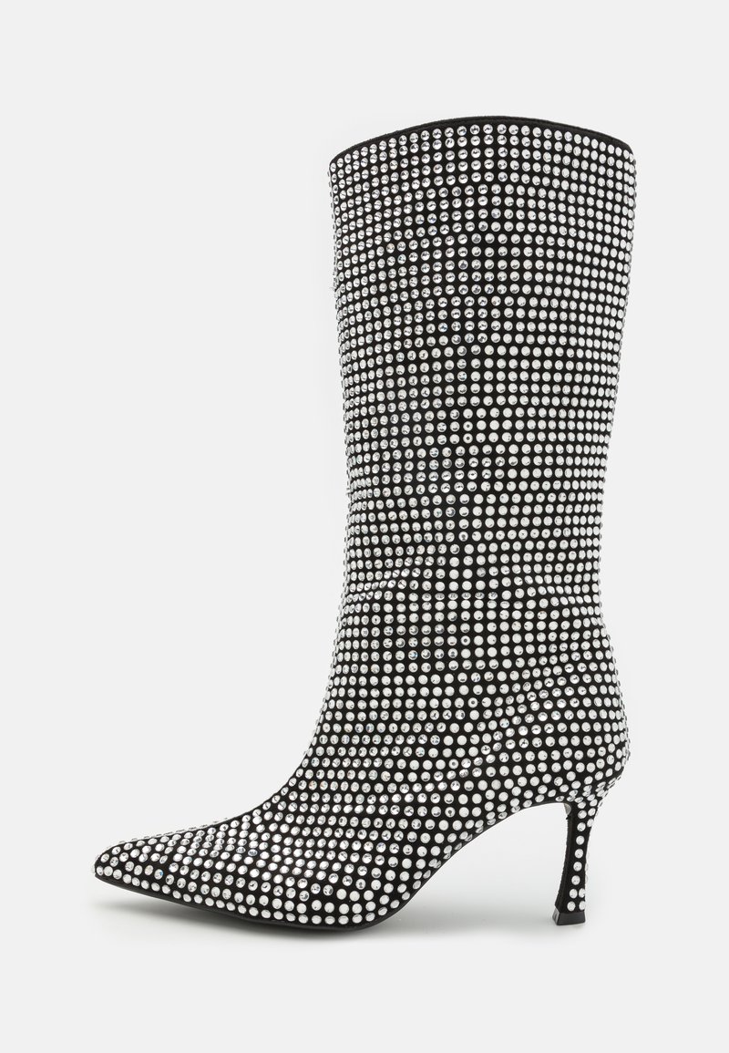 Botín negro con piedras brillantes, textura suave, punta afilada y tacón delgado. Presenta un diseño ajustado con acentos brillantes.