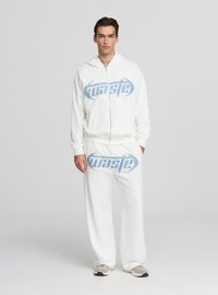 Completo con felpa con cappuccio e pantaloni della tuta bianchi con logo "waste" blu. Design con zip, tessuto morbido, vestibilità comoda, cuciture dettagliate, abbinato a scarpe chiare.