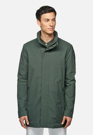 Chaqueta impermeable de color verde oscuro con un alto cuello, bolsillos laterales y una textura suave. Cuenta con un cierre de cremallera y botones a presión para un ajuste seguro.