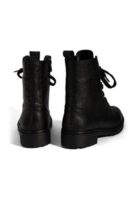 Schwarze, strukturierte Leder-Schnürstiefel mit seitlichen Reißverschlüssen, Zuglaschen an der Rückseite und dicken Gummisohlen, von hinten auf einem weißen Hintergrund dargestellt.