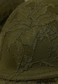 Olijfgroene kantstof met een verhoogd bladerenpatroon, vol textuur en ingewikkelde details. Rond gevormd met een gladde afwerking.