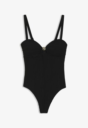 Schwarzer Einteiler mit strukturierten vertikalen Falten, Unterlegung mit Bügel-Cups, doppelte Schulterträger und kleiner metallischer Zierverschluss in der Mitte.