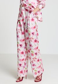 Bluse mit Blumenmuster und Hosen mit weitem Bein in Pastellfarben. Aus Seide gefertigt, mit pinken Blumen, grünen Blättern und angenehmer, lockerer Silhouette.