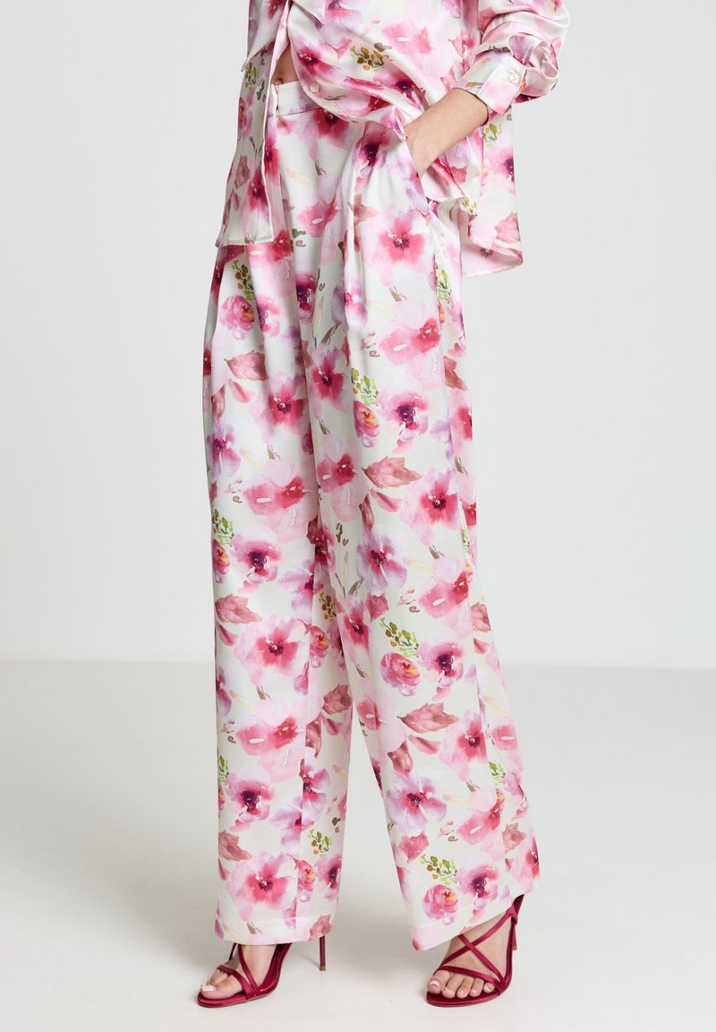 Bluse mit Blumenmuster und Hosen mit weitem Bein in Pastellfarben. Aus Seide gefertigt, mit pinken Blumen, grünen Blättern und angenehmer, lockerer Silhouette.