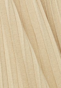 Gros plan sur un tissu tricoté côtelé beige avec des lignes verticales texturées et des plis doux.