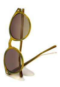 Pruunikad päikeseprillid läbipaistva kollakasrohelise raami, ümarate läätsede ja siledate, piklike küljelabadega.