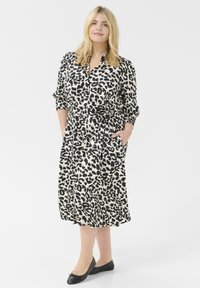 Luipaardprint jurk met een knoopsluiting aan de voorkant, korte mouwen, een ceintuur in de taille en zijzakken. Gemaakt van een lichtgewicht stof in neutrale tinten.