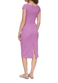 Aangesloten, roze midi-jurk met kapmouwen, een rechte silhoeët en een sleufdetail aan de achterkant. Model draagt sandalen met bandjes.