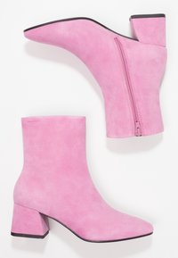 Rosa mocka ankelskor med spetsig tå, kraftig klack och sidodragkedja. Slät textur utan synliga mönster eller detaljer.