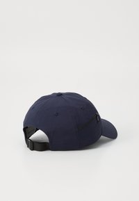 Casquette de baseball bleu marine avec une visière courbée, poche zippée sur le côté et une sangle réglable à l'arrière. Fabriquée en tissu léger.