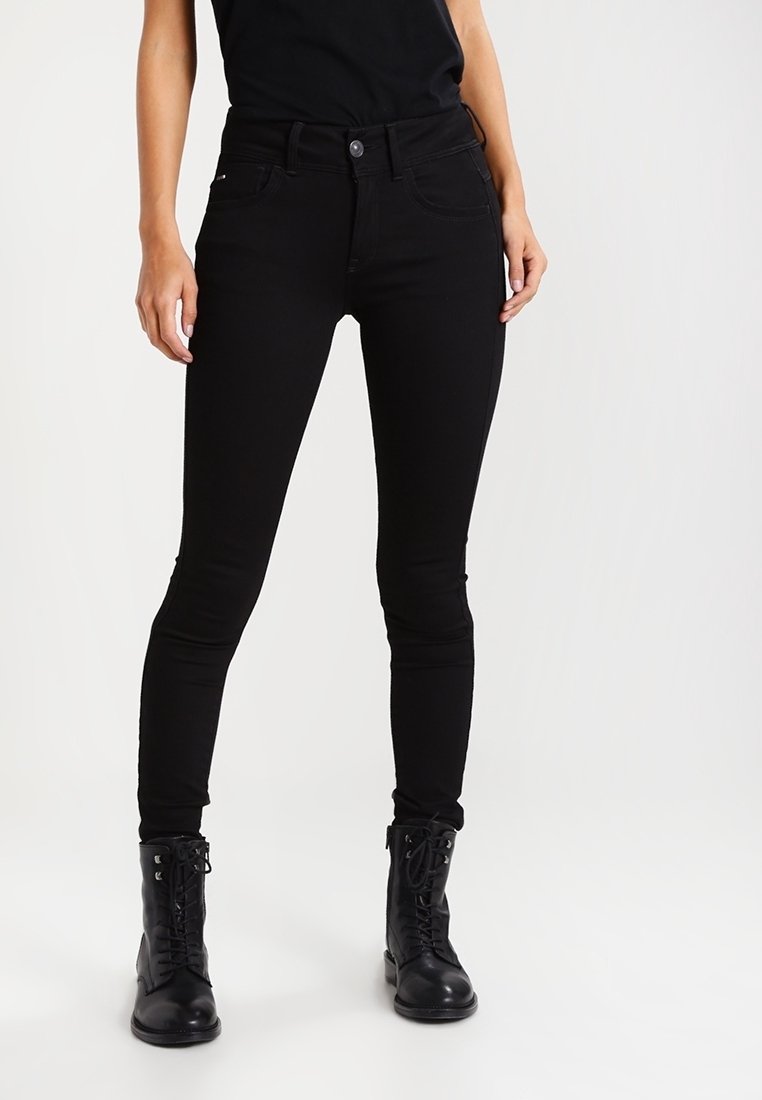 Jeans ajustados negros con una cintura alta, cinco bolsillos y una textura de tela suave. Combinados con botas negras de cordones.