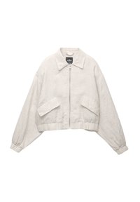 Veste courte beige clair en tissu texturé. Elle présente un col rabattable, une fermeture éclair à l'avant et deux grandes poches latérales avec poignets élastiques.