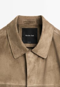 Brown suede jacket with a classic collar and hidden buttons. Features a black label reading "Massimo Dutti." Smooth, soft texture.