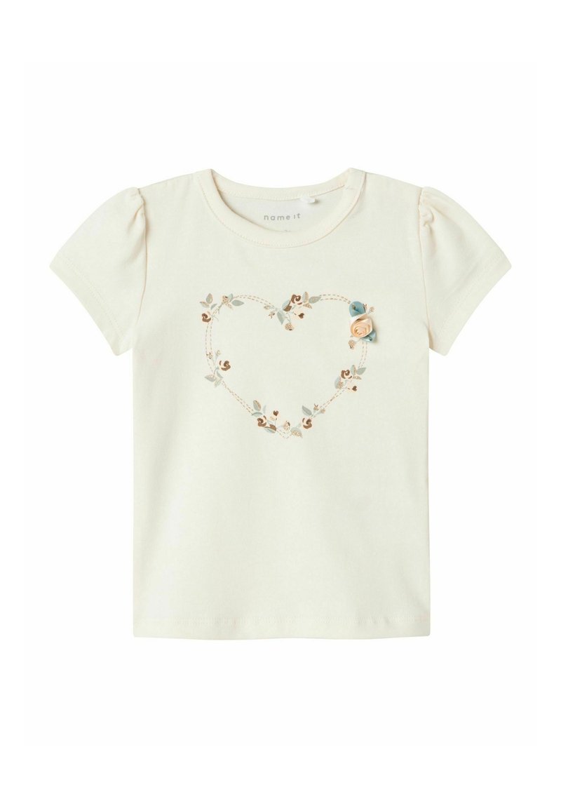 Kortærmet, cremefarvet bomulds t-shirt med et hjerteformet blomsterbroderi design og en lille stofrose accent på venstre side.