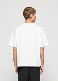 White cotton t-shirt with short sleeves and a relaxed fit. Features a round neckline and minimalistic design, with a small brand detail at the back.