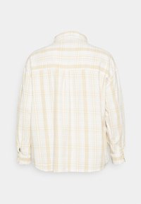 Camisa de botão com padrão xadrez em amarelo claro e branco. Mangas longas com punhos abotoados e um colarinho clássico. Textura de tecido suave.