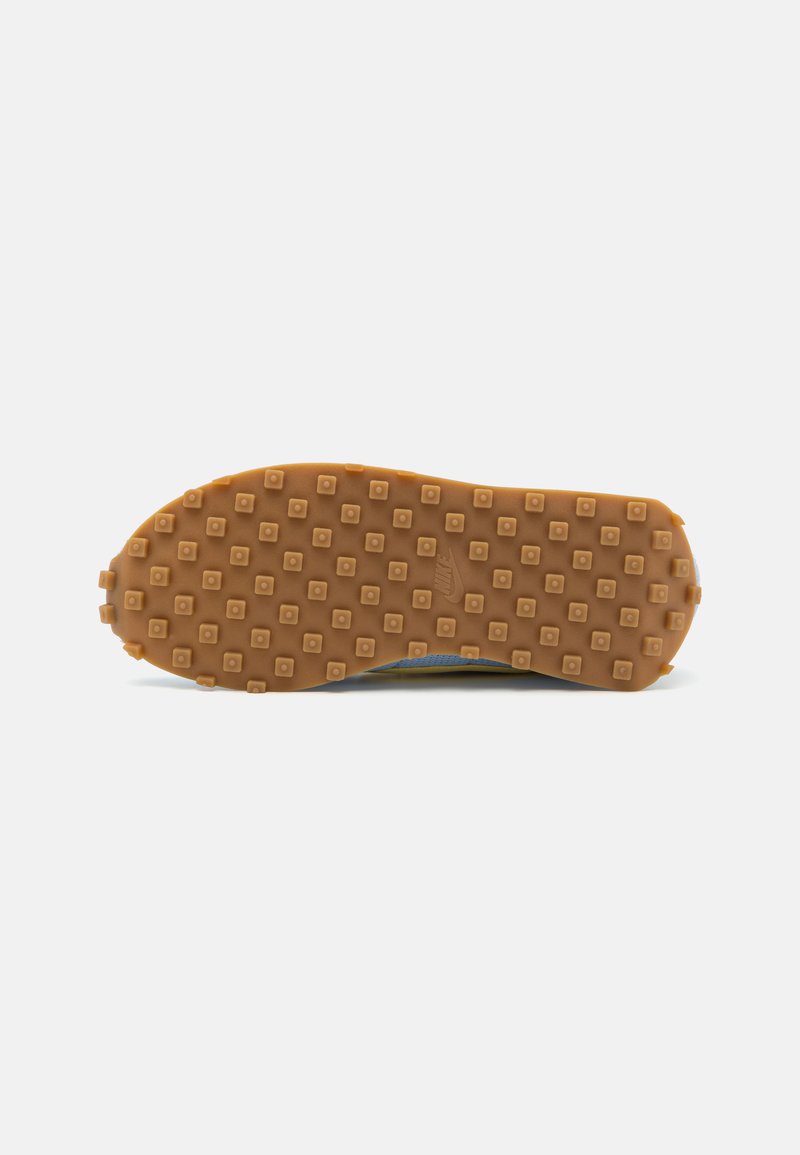Suela de goma con un diseño de agarre en patrón, que presenta cuadrados elevados en un color marrón claro. Superficie texturizada para mayor tracción.