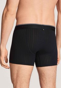 Zwarte boxer shorts van zacht fabric met een subtiel streeppatroon. Voorzien van een elastische waistband met logo en een aansluitend ontwerp.