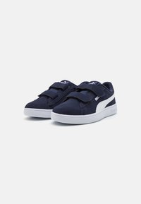 Baskets de sport bleu marine avec des straps en velcro, texture semblable au daim, semelle en caoutchouc blanc, et un logo discret sur le côté et sur la languette.