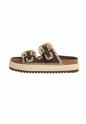 Brązowa sandałka typu klapki z dwoma złotymi klamrami, białym przeszyciem w zygzak, platformową podeszwą z juty i teksturowaną brązową podeszwą zewnętrzną.