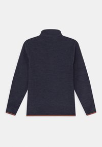 Tummansininen pitkähihainen neulepaita, jossa on korkea kaulus. Paidassa on heatheroitua tekstuuria ja kontrastiväristä oranssia ommelta hihansuissa ja helman ympärillä.