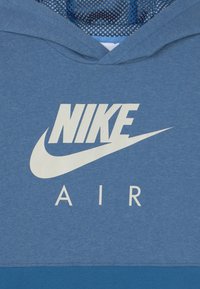 Marinblå hoodie med nätfoder, med en framträdande vit Nike-logotyp och orden "AIR" under i vit text.