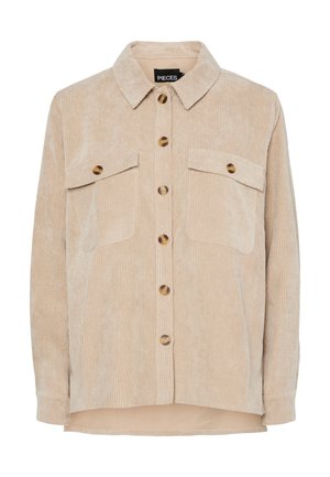 Beige värillinen puuvillahousupaita, jossa kauluksellinen pääntie, kaksi rintataskua ja suuret pyöreät napit. Pehmeä pinta, jossa pystysuuntaiset uritukset.