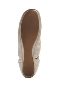Kremowy płaski but z gładką brązową podeszwą i miękką, lekko pofałdowaną skórzaną cholewką, widziany od strony podeszwy.