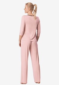 Miękki różowy zestaw piżamowy składający się z bluzki z rękawami o długości trzech czwartych i luźnych spodni, wykonany z lekkiego materiału w swobodnym kroju.