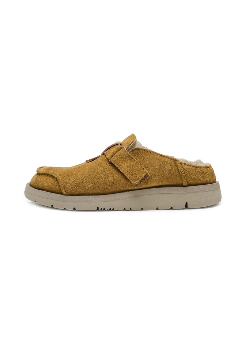 Zapatos de ante marrón tipo slip-on con un interior suave, que cuentan con un cierre de tiras y una resistente suela de goma beige.