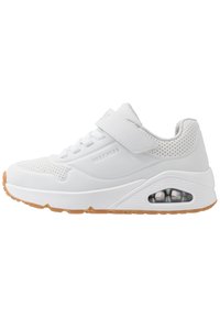 Witte sneaker met een geperforeerd ontwerp, veters en klittenbandsluiting, gevoerde zool en een transparant luchtbel-detail op de hiel.