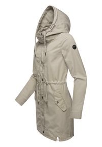 Light beige hooded jacket with drawcord, button closure, two front pockets, and a logo patch on the sleeve. Smooth, lightweight fabric.