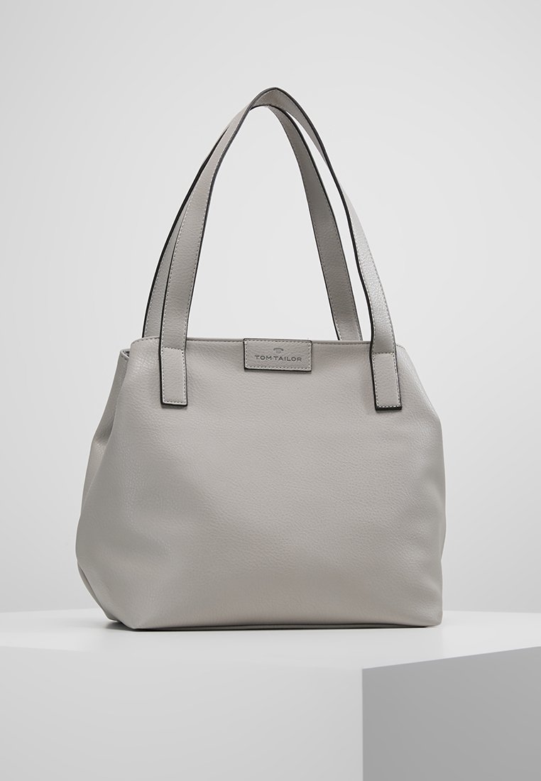 Sac fourre-tout en cuir gris avec une texture lisse, double anses, forme rectangulaire et garniture noire contrastante. Présente une plaque de logo à l'avant.