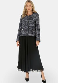 Niebieska, biała i czarna marynarka typu tweed z zaokrąglonym dekoltem, podwójnym zapięciem i guzikami w złotym odcieniu, zestawiona z czarną spódnicą.