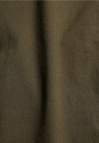 Gros plan sur un tissu vert olive montrant une fine texture de tissage diagonal et des plis subtils.