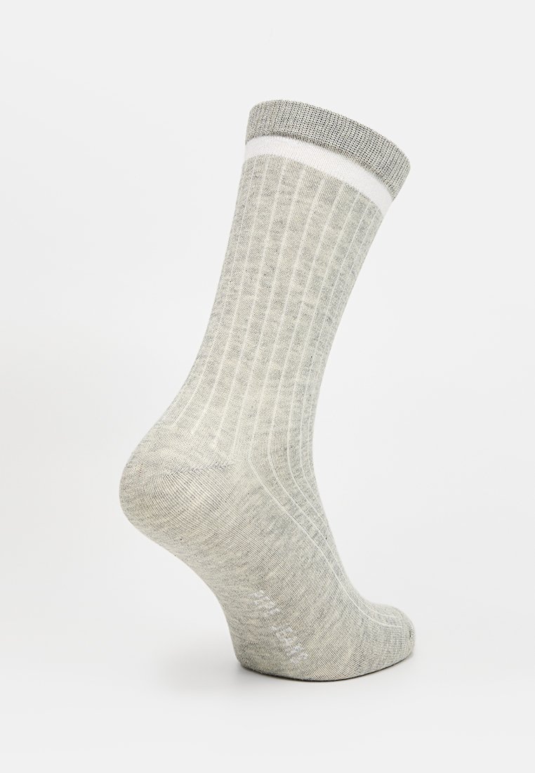 Calcetín gris con canalé y puño blanco, hecho de material suave; presenta una textura lisa y un diseño estructurado. Largo estándar hasta el tobillo.