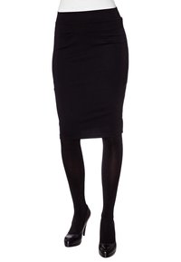 Musta kynähame, joka on valmistettu venyvästä kankaasta, istuu vyötäröllä ja siinä on muotoiltu siluetti, jota täydentävät läpinäkyvät mustat sukkahousut ja korkokengät.