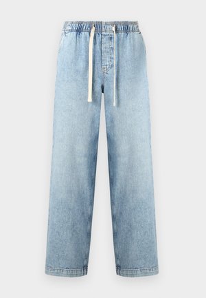 Φαρδιά τζιν παντελόνια σε ανοιχτό μπλε χρώμα με ελαστική μέση και λευκό κορδόνι, πάνω σε απλό φόντο.