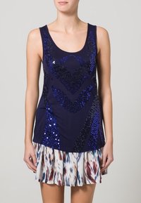 Top senza maniche blu navy con motivo di paillettes blu e scollatura a barca, abbinato a una gonna leggera plissettata con un design astratto multicolore.
