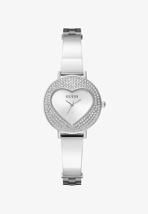 Ezüst Guess karóra szív alakú számlappal, kristályokkal díszített lünettával és elegáns fém karkötőszíjjal.