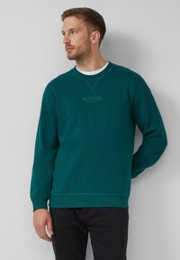Felpa teal con maniche lunghe, collo rotondo, polsini e orlo a coste. Presenta un piccolo logo stampato sul petto e un colletto interno bianco.