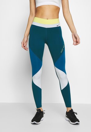 Leggings taille haute teal et bleus avec des accents blancs et jaunes, arborant un logo "Just Do It". Tissu lisse et extensible pour le sport.
