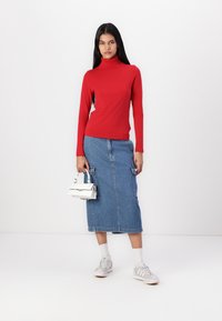 Rød høyhalset skjorte, denim midi skjørt med sidelommer, hvit veske og grå sneakers. Glatt stoff og uformelt design.
