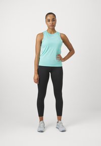 Lys turkise trenings-top kombinert med svarte leggings. Toppen har en tett passform og myk tekstur, mens leggingsene er glatte og elastiske.