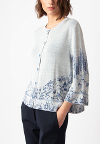 Light gray cardigan with blue landscape pattern, button front, ribbed cuffs, and hem. Made from soft material, featuring a loose fit.